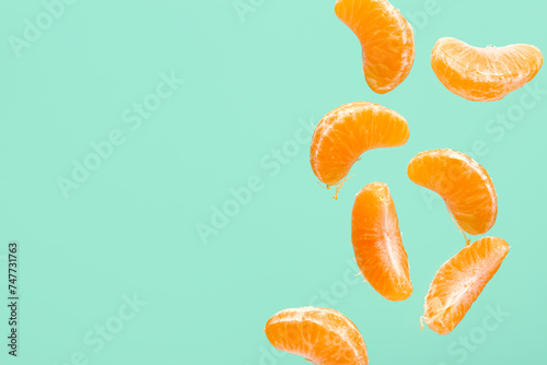 Flying pieces of sweet peeled mandarin on turquoise background