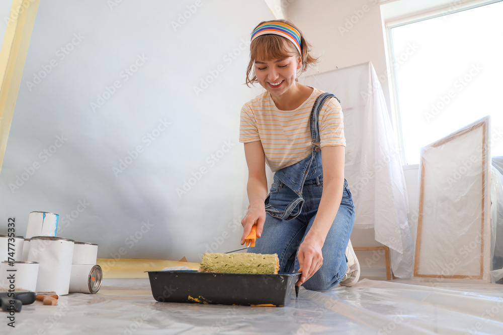 © Pixel-Shot - Young woman with paint roller doing repair in room