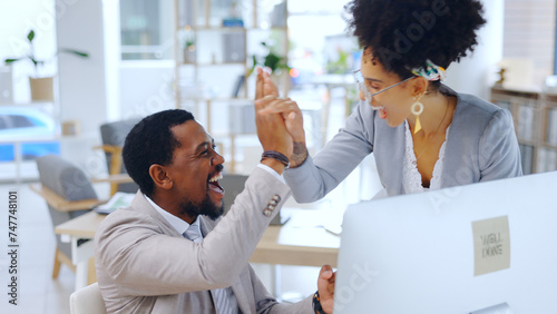 Excited, business people and high five with computer at office for team success or achievement. Happy man and woman employee or colleagues touching hands for winning, promotion or deal at workplace photo