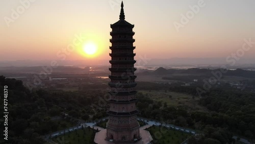 Drone aerial view in Vietnam flying around a buddhist pagoda in a Ninh Binh temple at sunset with green landscape in the horizon photo