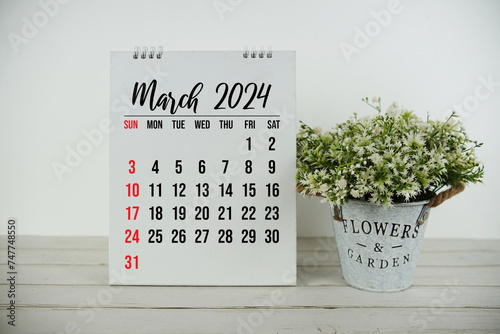 March 2024 monthly calendar with vintage alarm clock on wooden background photo