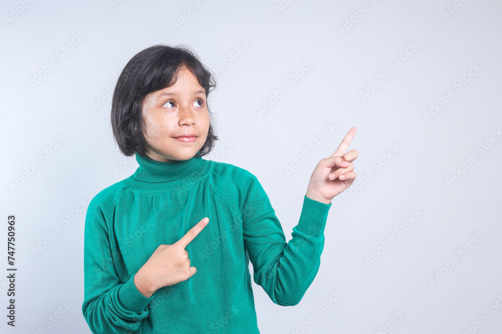 Little Asian girl pointing to the side showing copy space for advertisement. Little Asian girl pointing to the side showing copy space for advertisement.