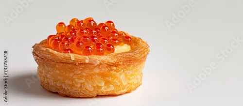 A small pastry made of wheat, topped with jelly made from red caviar. The pastry looks delectable and appetizing, with a white background enhancing its visual appeal.