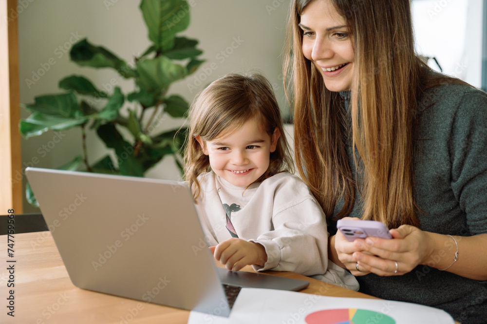 freelancer mother with daughter working in home office, hybrid work