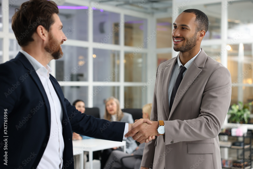 Lawyer shaking hands with client in office, selective focus Lawyer shaking hands with client in office, selective focus