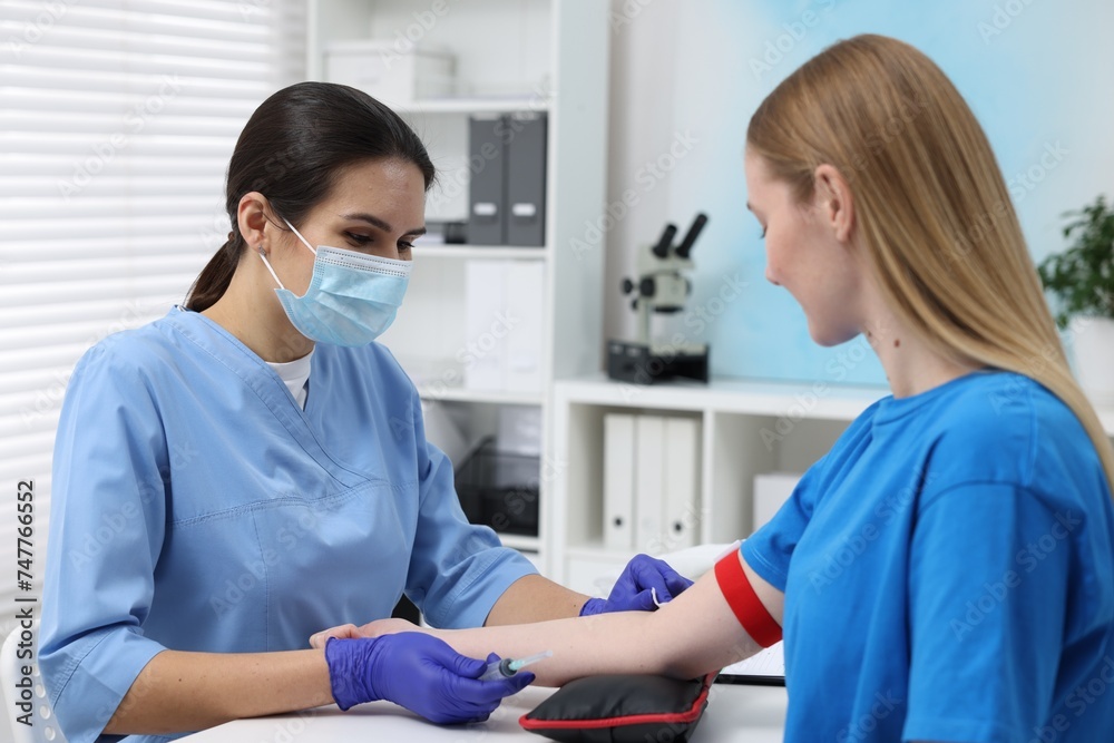 Fototapeta premium Laboratory testing. Doctor taking blood sample from patient at white table in hospital