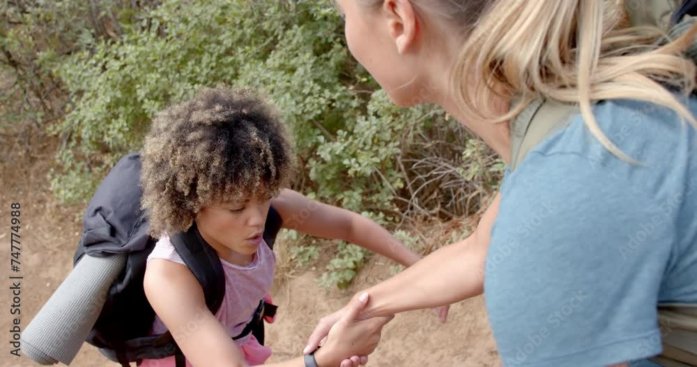 A young child with curly hair receives help from a woman outdoors A young child with curly hair receives help from a woman outdoors