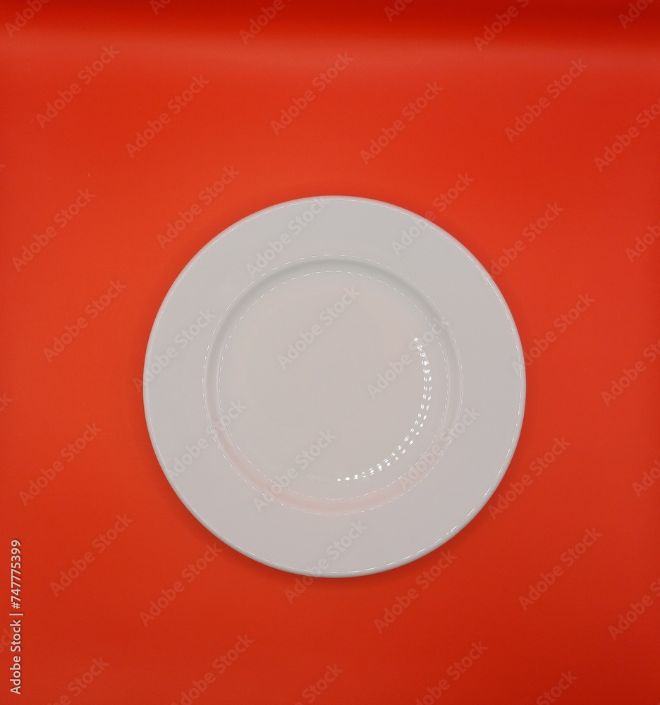 Top view of empty white plate on red background. Meal preparation concept. Top view of empty white plate on red background. Meal preparation concept.