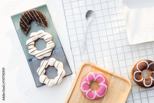 Flat lay composition of five colordul doughnuts on a  plate. Delicious unhealthy donuts on the table. photo