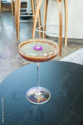 Classic cocktail glass with flower on glass table in night club.