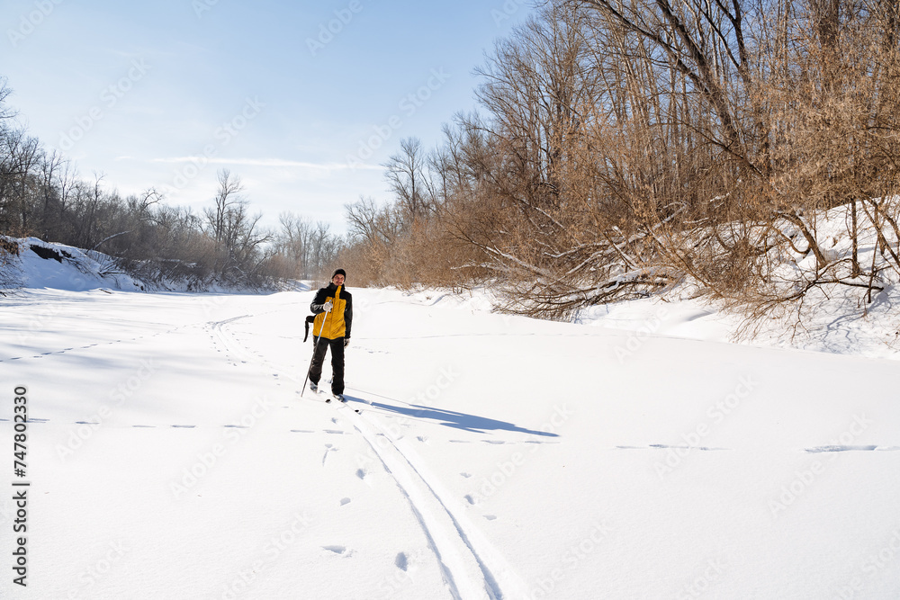 Man skiing on a winter river, solo hiking in a snowy forest, trekkig on a frozen lake.