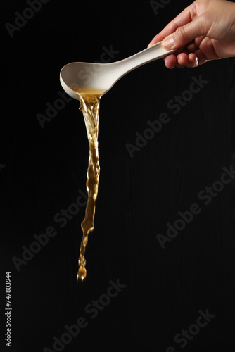 Dipper pouring noodle soup on black background, Soup for sukiyaki from chicken and fish