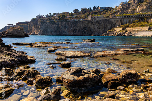 Rocks and cliffs of Capo Taormina cape on Ionian sea shore of Taormina, Giardini Naxos and Villagonia towns in Messina region of Sicily in Italy photo