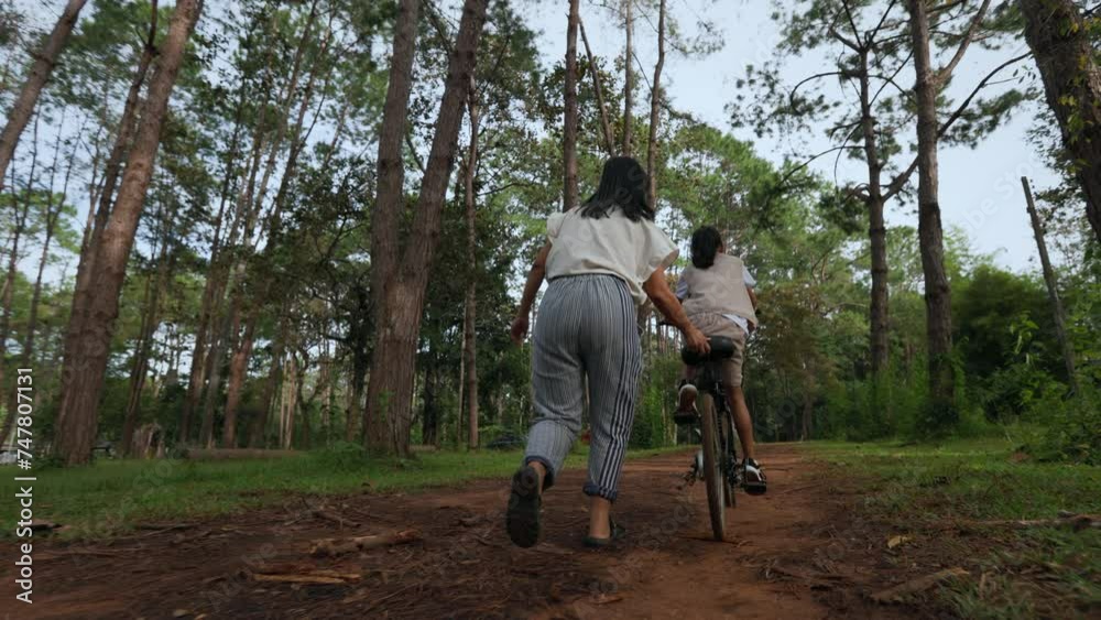 Asian child girl riding the bicycle and mother running beside. Asian child girl riding the bicycle and mother running beside.