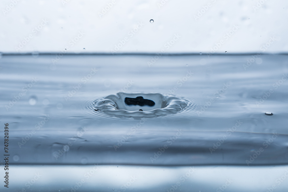 A drop bouncing off clean, clear water, creating a splash effect A drop bouncing off clean, clear water, creating a splash effect