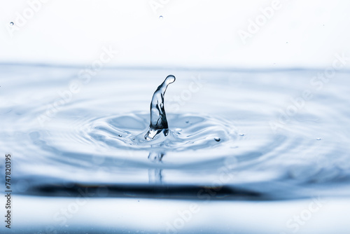 A drop bouncing off clean, transparent water, creating a splash effect and a shape resembling a hunched person