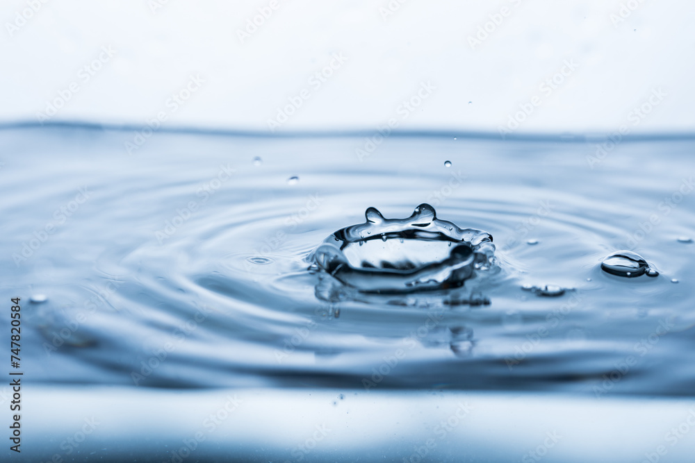 A drop bouncing off clean, clear water, creating a splash effect A drop bouncing off clean, clear water, creating a splash effect