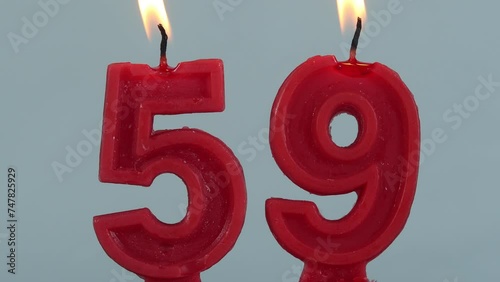 close up on timelapse melting a red number fifty ninth birthday candle on a white background.
 photo