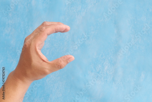 Obraz na płótnie Young male Asian hand making letter C sign isolated on blue background. w salonie