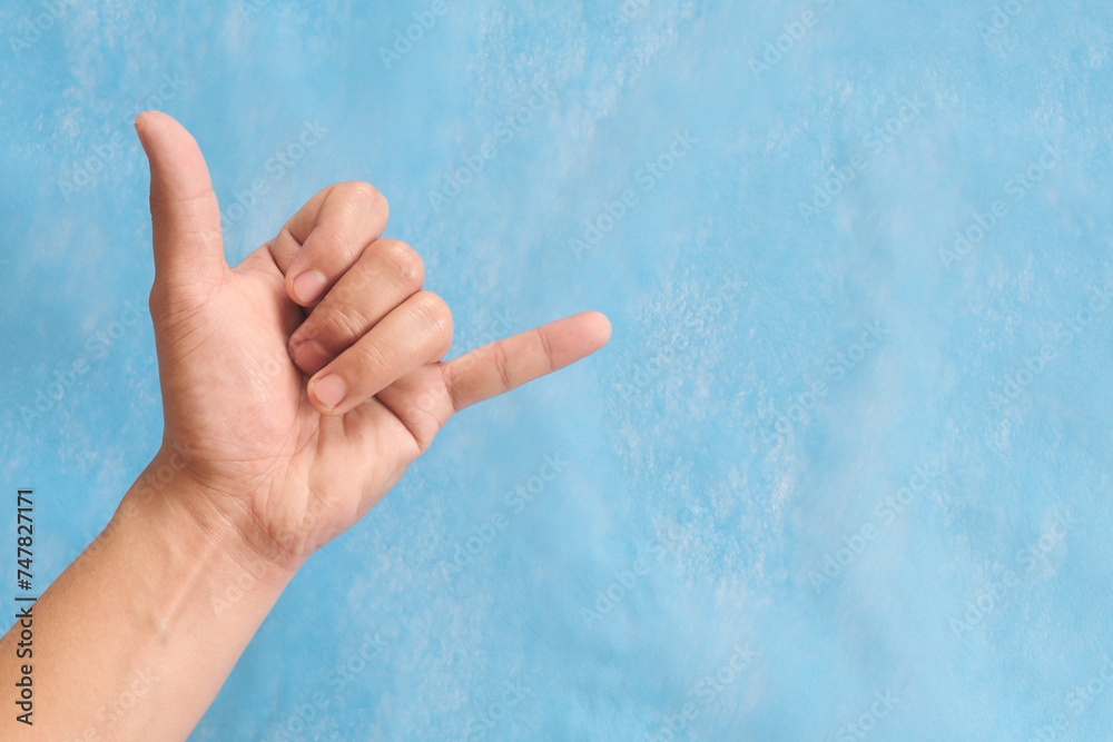 Young male Asian hand making shaka sign or call me sign isolated on blue background.