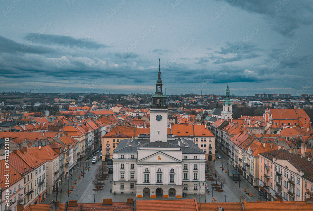 illuminated night view of the town hall in Kalisz, Poland from a drone, dramatic blue sky before rain, view of old tenement houses and architecture