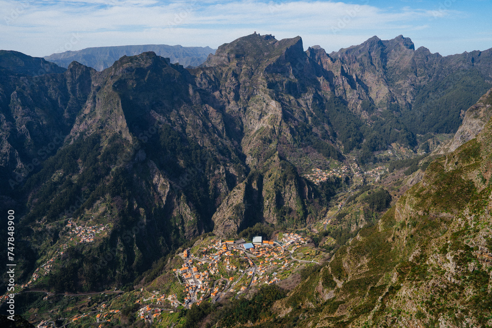View of the village of Curral das Freiras (Corral of the Nuns) overlooked by the Pico Grande summit from the Miradouro do Paredão viewpoint in the Valley of the Nuns on Madeira island, Portugal