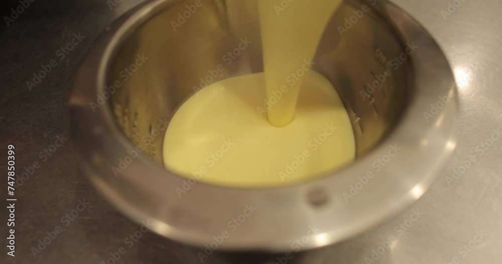 A pastry chef pours dessert mixture into a bowl. Cake making process close-up. A pastry chef pours dessert mixture into a bowl. Cake making process close-up.