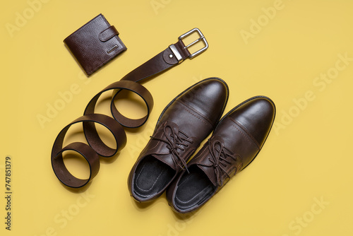 Men's accessories on beige background. Leather brown classic shoes, wallet and belt. Casual design, fashion concept. Flat lay, top view