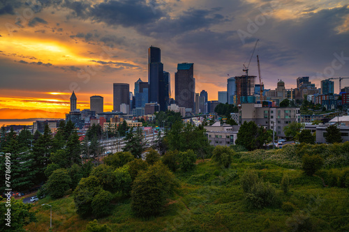 Dramatic sunset over Seattle skyline with visible greenery in the foreground, viewed from Dr. Jose Rizal Bridge.