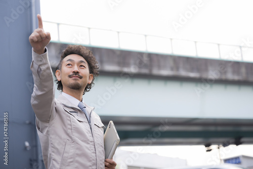 Middle-aged worker in work clothes looking up outdoors with the viaduct in the background Pointing out goals and images of the future
