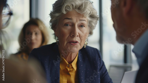 Senior professional woman engaging in a serious discussion during a business meeting.