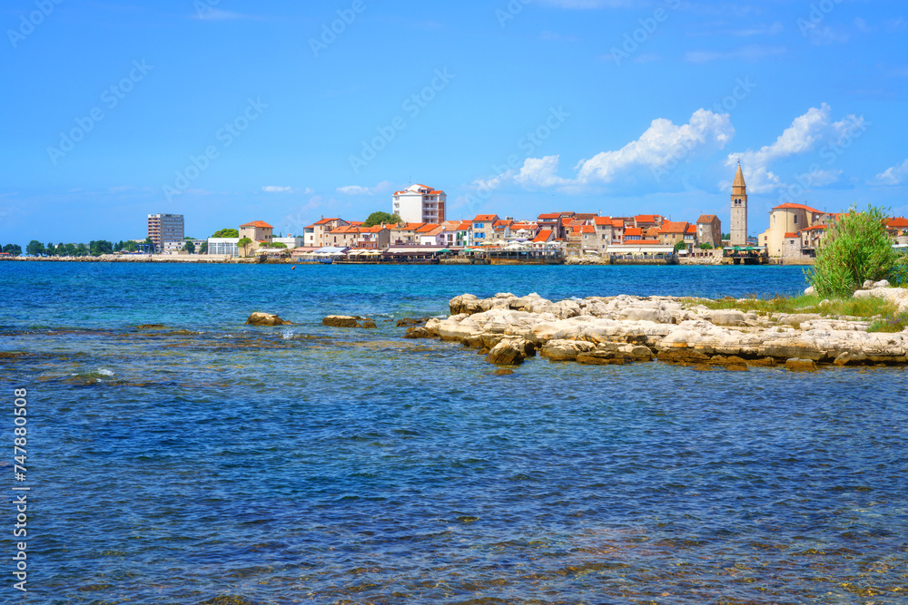 Scenic view of the Umag old town, Adriatic seacoast, Istria, Croatia. Summer landscape with medieval architecture, clear blue sea water and sky with clouds, outdoor travel background