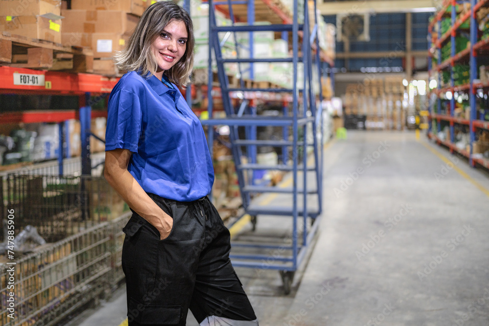 Confident female warehouse worker standing in logistic storage looking at camera smiling. Caucasian supervisor employee working in shipping distribution storehouse. Inventory manager in workplace.