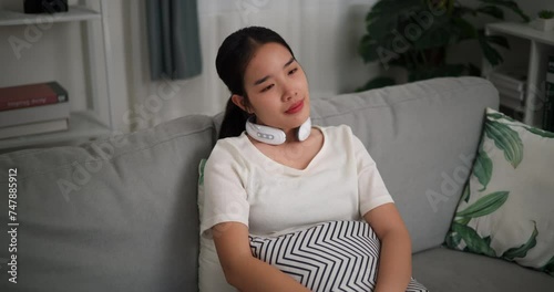 Footage dolly shot, Relaxed young woman wear automatic massage neck at home with eyes closed, relaxing body and mind alone in the living room, breathing fresh air, photo