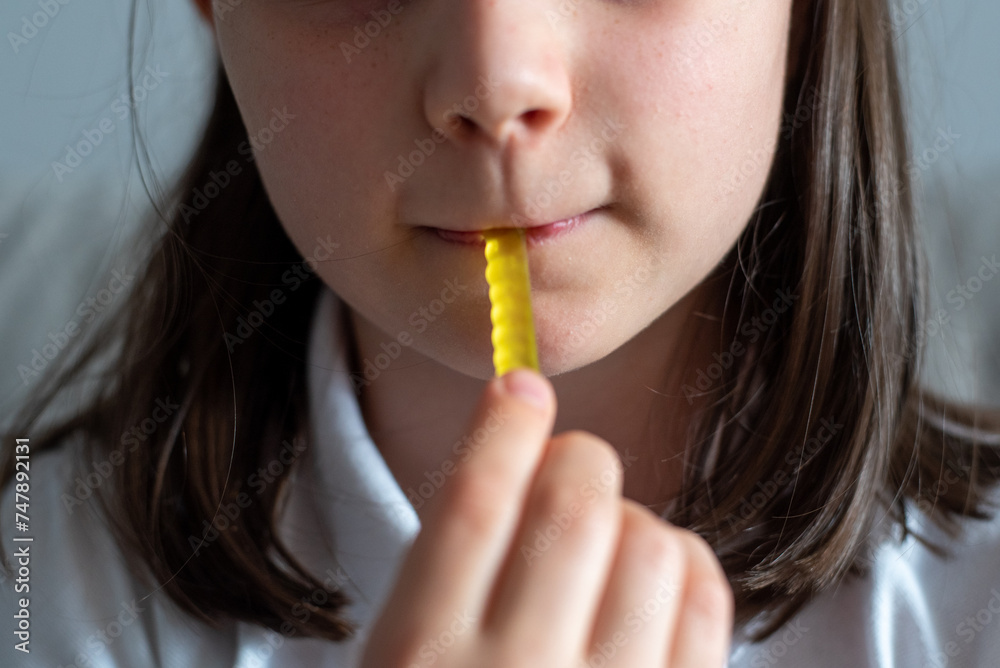 Schoolgirl Eating Gummy Worms Candy: Close-Up of Mouth Schoolgirl Eating Gummy Worms Candy: Close-Up of Mouth