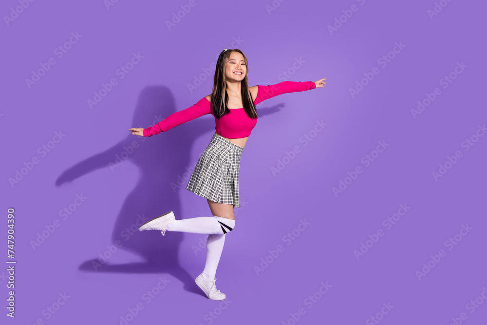 Full body photo of carefree cute schoolgirl wear crop top plaid skirt long socks holding arms like wings isolated on violet background