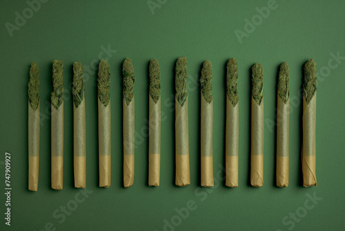 A neatly rolled cannabis joints on a vibrant green background, overhead flat lay studio shot