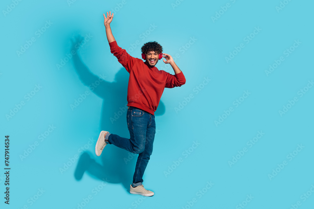 Full size portrait of nice positive young man enjoy favorite song dancing empty space isolated on blue color background Full size portrait of nice positive young man enjoy favorite song dancing empty space isolated on blue color background