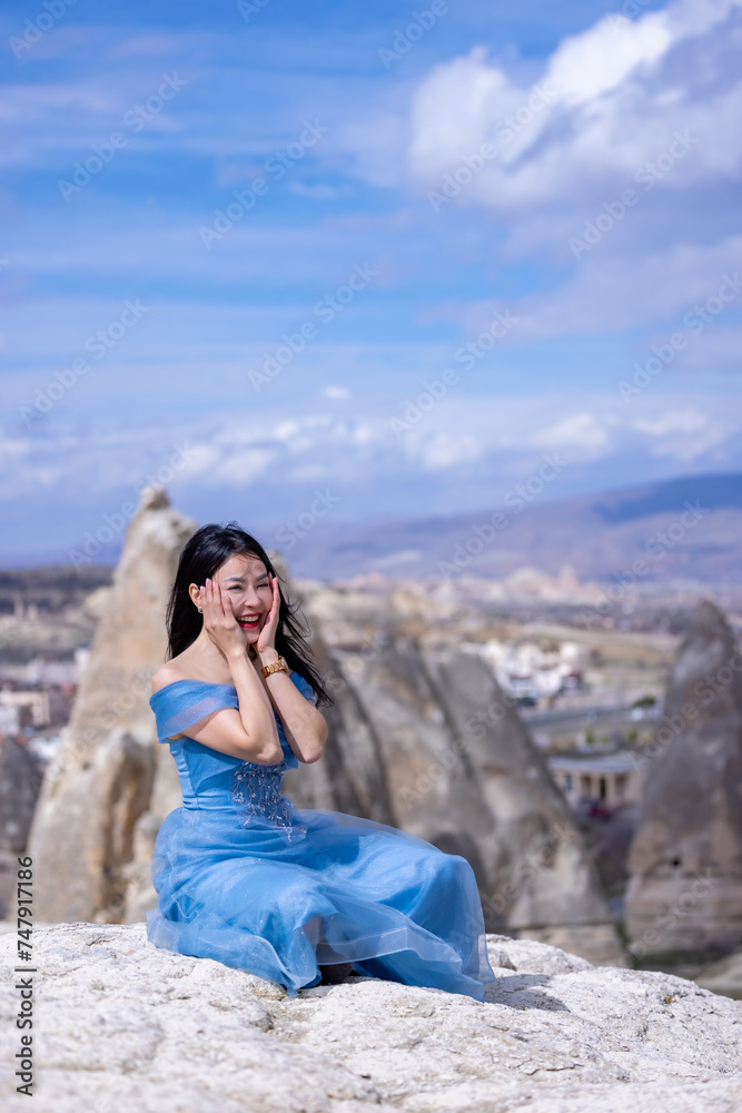 Beautiful woman in blue dress on rocks mountain. Cheerful woman relax outdoor with beautiful sky and pink flowers in holiday vacation. Woman tourist enjoy amazing mountain view. Travel and freedom.. Beautiful woman in blue dress on rocks mountain. Cheerful woman relax outdoor with beautiful sky and pink flowers in holiday vacation. Woman tourist enjoy amazing mountain view. Travel and freedom..