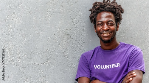 Smiling man with dreadlocks wearing pu rple volunteer t-shirt. photo