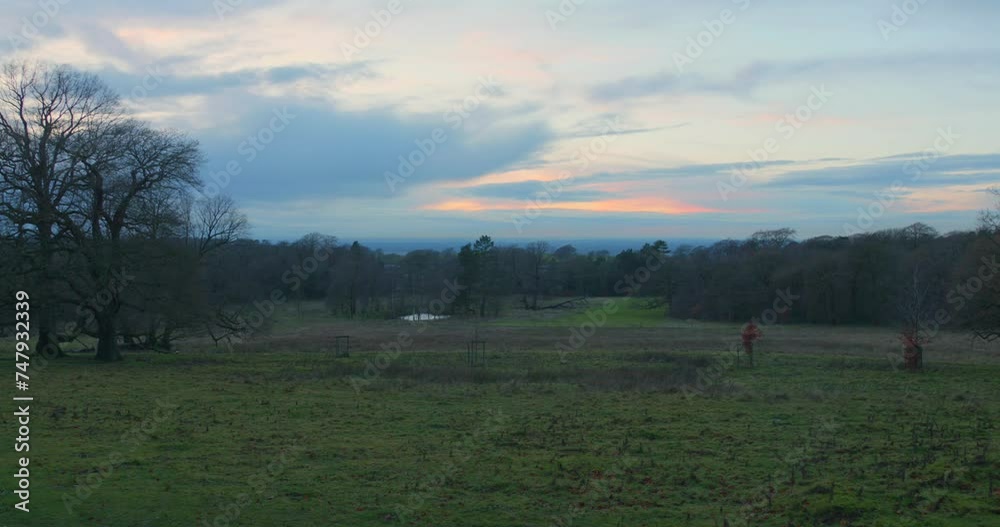 Twilight descends over Lyme Park with a fiery sky backdrop, bare trees in winter