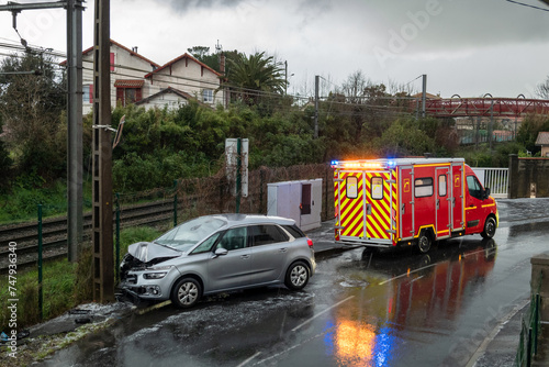 Carro acidentado contra um poste num dia frio e gelado de inverno e uma ambulância no resgate dos feridos photo