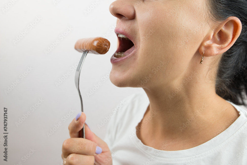 Naklejka premium Close-up of a woman eating a sausage.