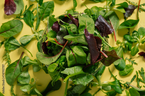 Healty food. Green leaves on a yellow table