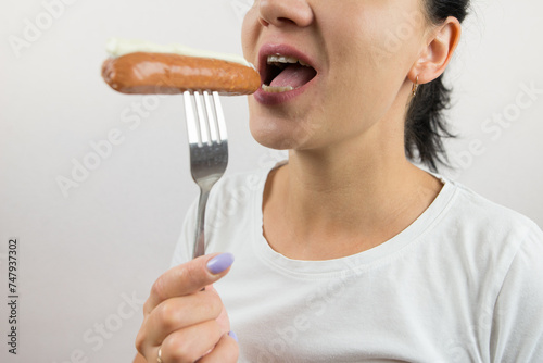 Close-up of a woman eating a sausage.