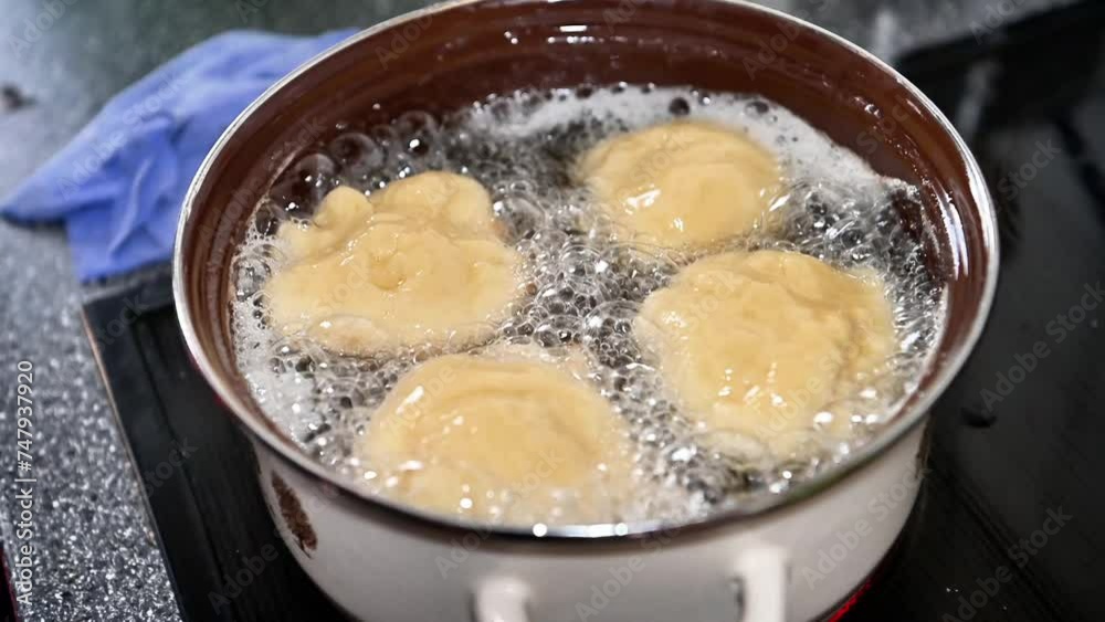 Berliner or doughnut cooking traditionally at home in a pot, close-up in slow motion. Add new dough. Boil oil and fat, hot temperature with bubbling Berliner or doughnut cooking traditionally at home in a pot, close-up in slow motion. Add new dough. Boil oil and fat, hot temperature with bubbling