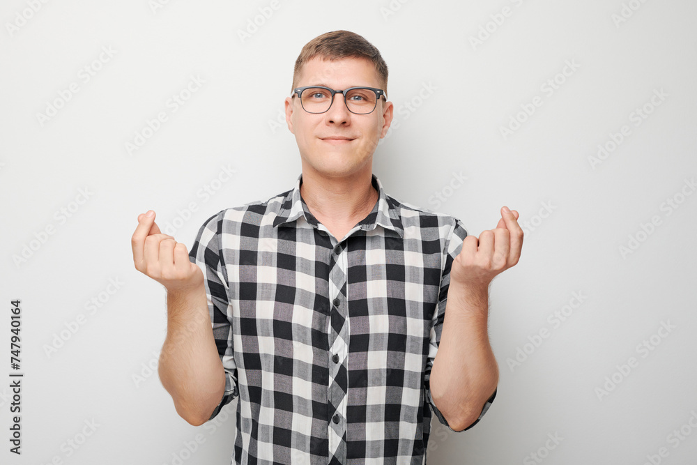 Young man in checkered shirt and glasses crossing fingers for good luck against a white background. Young man in checkered shirt and glasses crossing fingers for good luck against a white background.