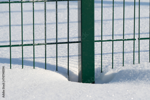A metal fence in a park covered with snow and frost.