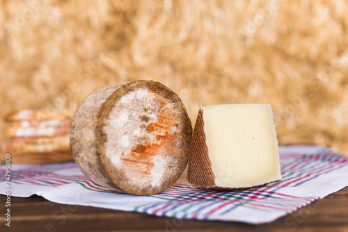 Whole head of ripe country cheese and slices on hay