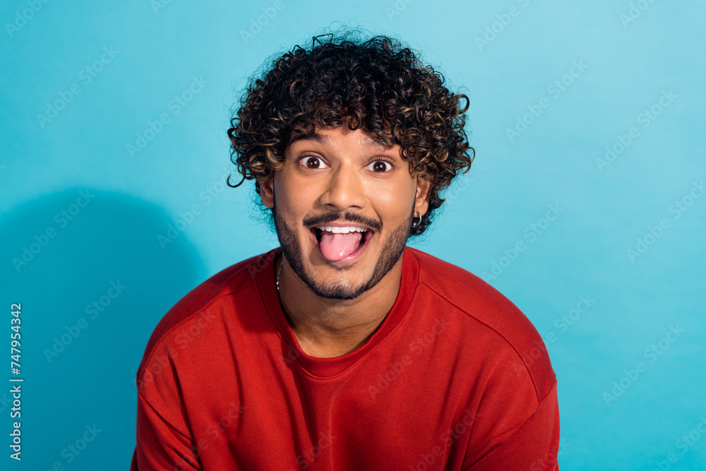 Portrait of positive carefree person have good mood showing tongue out isolated on blue color background Portrait of positive carefree person have good mood showing tongue out isolated on blue color background
